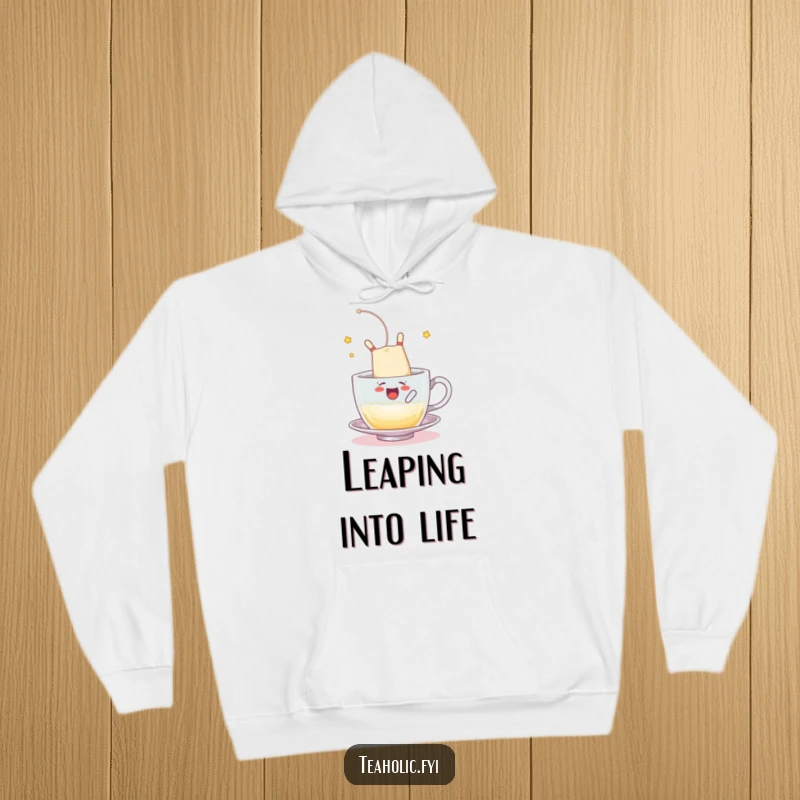 Funny hoodie with a tea bag character somersaulting into a frothy cup, a cozy funny gift.